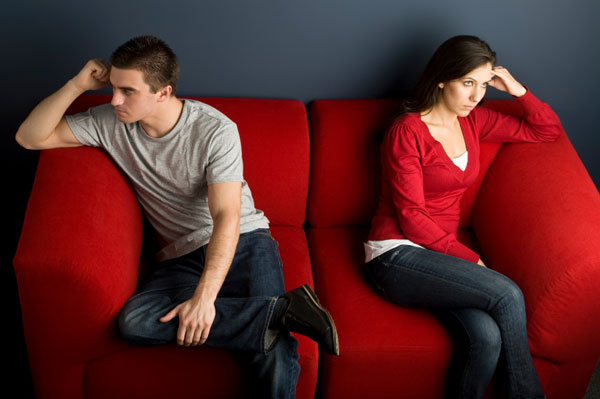 man and woman angrily looking away from each other on red couch